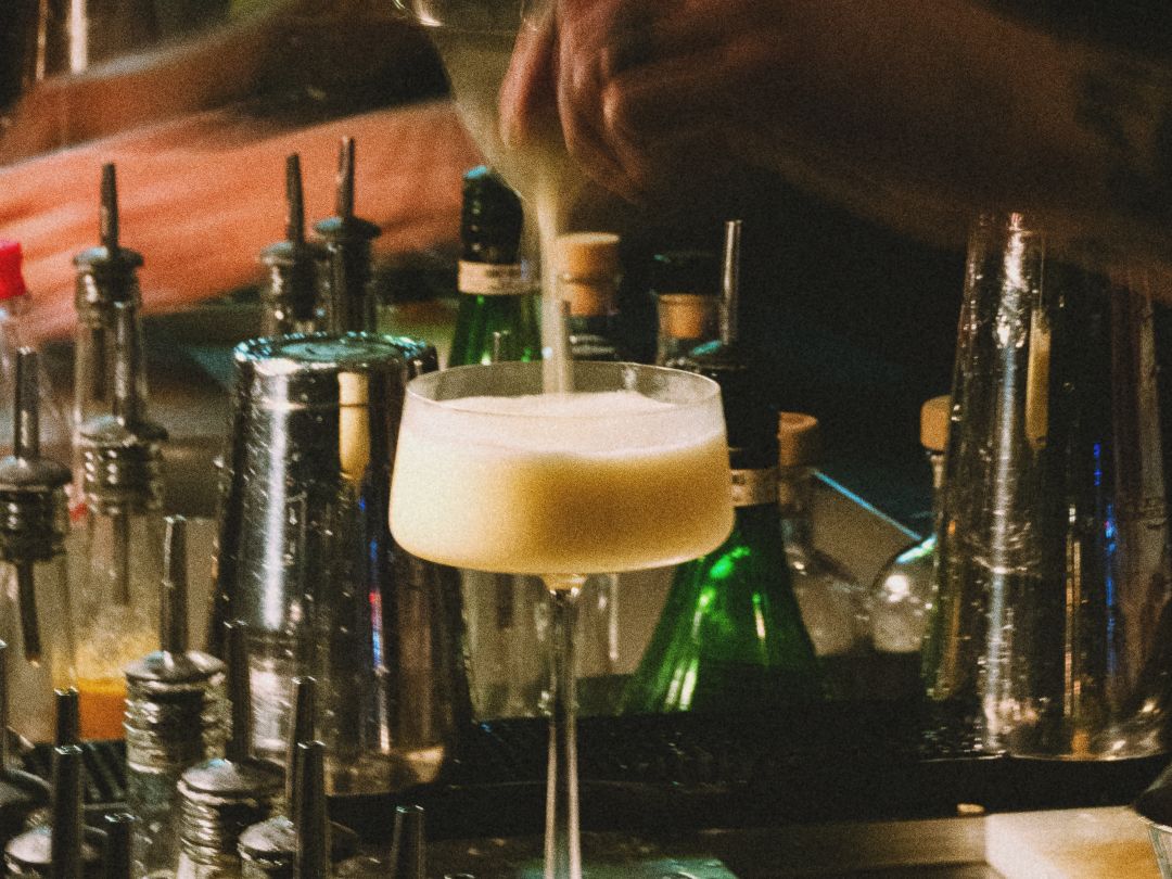 Bartender straining a sour